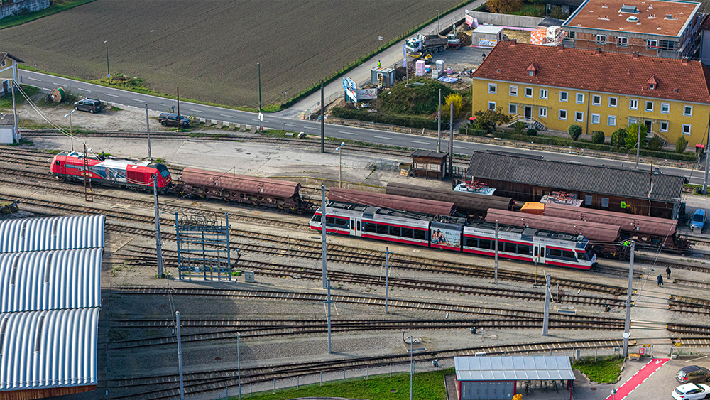 Blick auf einen Güterzug und einen Personenzug am Bahnhof Eferding von oben.