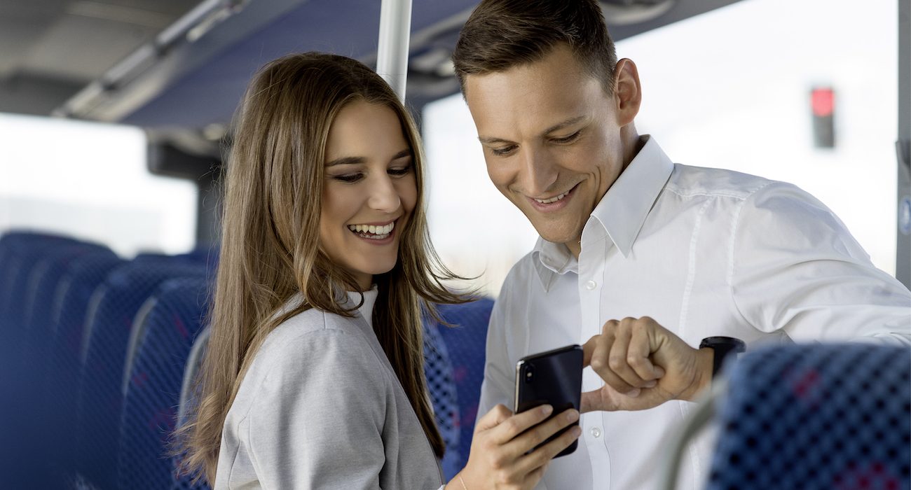 Mann und Frau im Bus mit Blick auf ein Smartphone